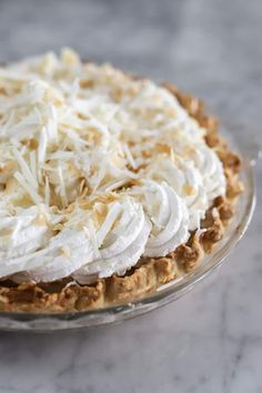 a pie topped with whipped cream on top of a glass plate next to a fork