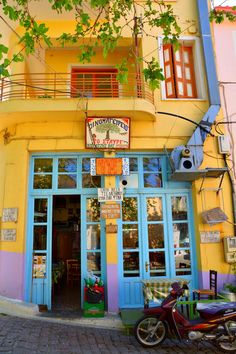 a motorcycle parked in front of a yellow building with blue doors and balconies