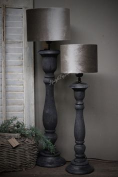 two lamps sitting next to each other on top of a wooden floor near a basket