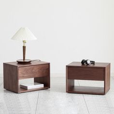 two wooden tables sitting on top of a white floor next to each other with a lamp