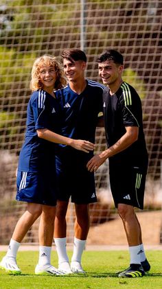 two men and a woman standing together on a soccer field