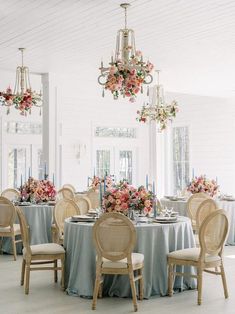 an elegant dining room set up with flowers and chandeliers