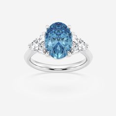 a blue and white diamond ring with three stones on the side, set in 18k white gold