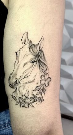 a woman's arm with a horse and flowers tattoo on the left side of her body