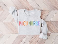 a sweater with the word cicu nurse on it sitting on top of a wooden floor