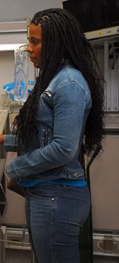 a woman with long hair standing in front of a machine and looking at something on the counter