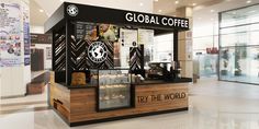 a starbucks coffee stand in the middle of a mall with people walking around it and there is also a sign that says, global coffee try the world