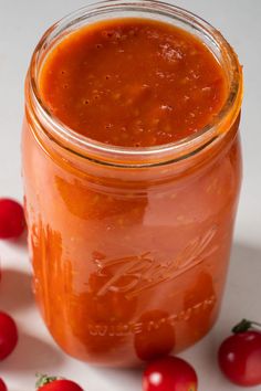 a jar filled with tomato sauce next to some tomatoes