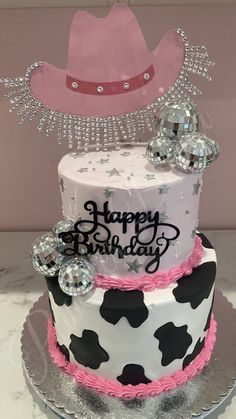 a birthday cake decorated with cow print and pink icing, has a cowboy hat on top