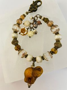 This bracelet is made up of a beautiful amber Czech glass elephant bead, an assortment of  Czech glass beads, antique gold spacer beads and an antique gold flower lobster clasp.  Dangles are Czech glass.  The total length of the bracelet is 7-1/2" with the beading section being 6-1/2".  It is slightly adjustable by about 1/2' and more can be added on request.  My  wrist is 6" and it fits perfectly on the shortest setting. Gold Beaded Bracelets With Large Czech Glass Beads, Bohemian Gold Beaded Glass Bracelets, Gold Bohemian Glass Beaded Bracelets, Handmade Brown Beaded Bracelets With Czech Glass, Handmade Czech Glass Brown Beaded Bracelets, Handmade Brown Czech Glass Beaded Bracelets, Bohemian Brown Czech Glass Bracelets, Vintage Czech Glass Beaded Bracelets With Large Beads, Unique Gold Beaded Glass Bracelets