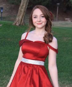 a young woman in a red dress posing for a photo with her hand on her hip