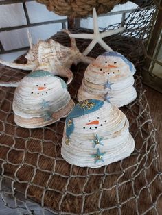 three snowmen made out of shells sitting on a table next to a starfish