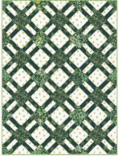 a green and white checkered quilt with flowers on the border, in front of a black background