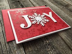 a red and white christmas card with snowflakes on the front, which reads joy