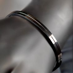 Sleek metallic bracelet or bangle with a polished finish. Modern Black Bracelets, Modern Gunmetal Bracelets For Formal Occasions, Modern Metal Cuff Bracelet, Modern Stainless Steel Bangle, Modern Cuff Bangle Bracelet, Modern Adjustable Cuff Bracelet, Adjustable Sleek Cuff Bracelet Bangle, Modern Stainless Steel Bangle Cuff Bracelet, Modern Stainless Steel Cuff Bracelet