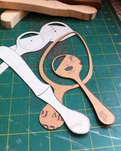 some scissors are cut out and placed on a green cutting mat next to a piece of wood