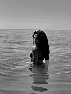 a woman is sitting in the water with her back turned