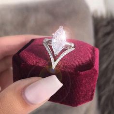 a woman's hand holding an engagement ring in a velvet box