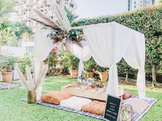 a white canopy bed sitting on top of a lush green field