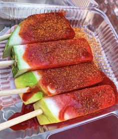 four popsicles with toppings in a plastic container