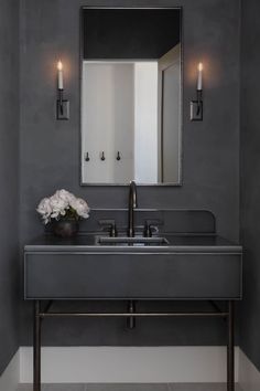 a bathroom sink sitting under a mirror next to a wall mounted faucet with two candles on it