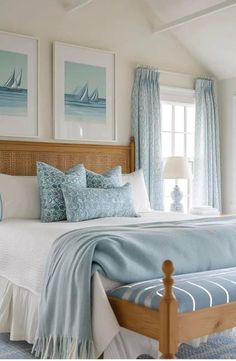 a bedroom with blue and white bedding, pillows and pictures on the wall above it