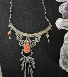 Stone and metal (likely brass) silver toned ornate necklace with natural coral colored stones. Handmade in Peru. 10 inches from top of hook clasp to bottom of dangling metal decoration. The metal is matte in appearance. Silver Bohemian Drop Necklace, Silver Wire Wrapped Bohemian Necklaces, Silver Wire Wrapped Bohemian Necklace, Bohemian Silver Carnelian Necklaces, Bohemian Copper Necklace In Silver Color, Bohemian Silver Necklace With Copper, Bohemian Silver Necklace In Copper, Silver Carnelian Bohemian Necklaces, Silver Carnelian Bohemian Necklace