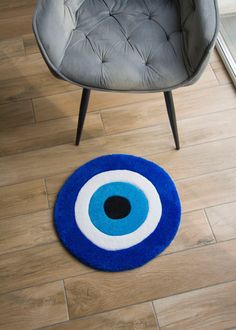 a blue rug with an evil eye in the center on a wooden floor next to a gray chair