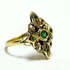 Very unique victorian ring with a 5 real emeralds The ring shape with a gentle engraving on the top And with a gentle design in the under part. the middle stone is a 4mm emerald + 4 small emerald stones 1.5 mm each LENGTH : 2.3 CM WIDTH : 1.5 CM Victorian Oval Yellow Gold Emerald Ring, Elegant 14k Stamped Emerald Ring, Victorian Oval Emerald Ring In Yellow Gold, Vintage Green Emerald Ring With Rose Cut Diamonds, Antique 14k Stamped Emerald Ring, Antique Hallmarked Emerald Ring, Victorian Emerald Jewelry In Yellow Gold, Antique Emerald Ring In Stamped 14k Yellow Gold, Victorian Emerald Ring In Yellow Gold