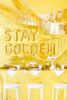 an image of a golden bar set up with white stools and gold foil decorations