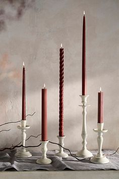 a group of candles sitting on top of a table next to each other in front of a wall