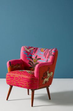 a pink chair sitting on top of a white floor next to a blue painted wall