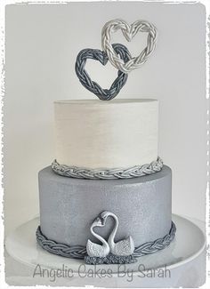 a three tiered cake with two swans on the front and one heart on the back