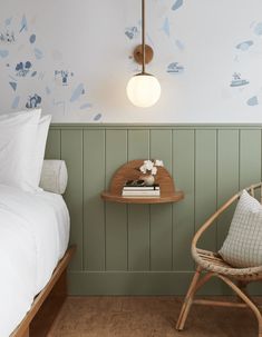 a bedroom with green paneling and white bedding has a wooden chair next to it