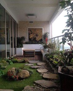 an outdoor area with grass, rocks and plants on the side of the building that has glass doors to let in light