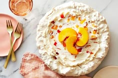 there is a pie with peaches on top and two forks next to it, along with pink plates