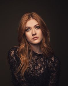 a woman with long red hair is posing for a photo in a black lace top