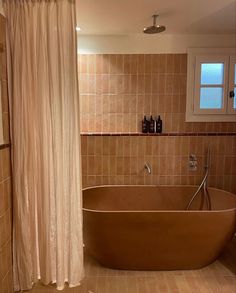 a bath tub sitting in the middle of a bathroom next to a shower head and window