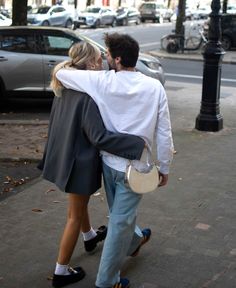 a man and woman are walking down the street with their arms around each other as they hug