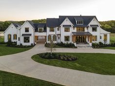 a large white house with lots of windows on it's front lawn and driveway