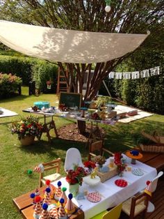 an outdoor party setup up in the backyard with decorations and food on it's table