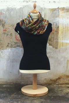 a mannequin wearing a black top and multicolored knitted cowl