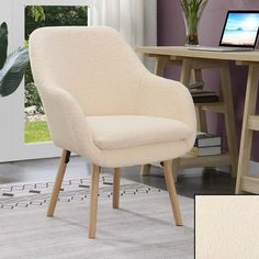 a white chair sitting on top of a rug next to a table with a laptop