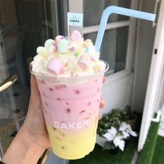 a person holding up a drink with marshmallows on it and a straw