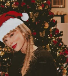 a woman wearing a santa hat next to a christmas tree