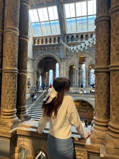 a woman is standing at the top of a staircase in a building with many pillars