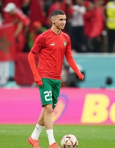 a soccer player in red and green is playing with a soccer ball on the field