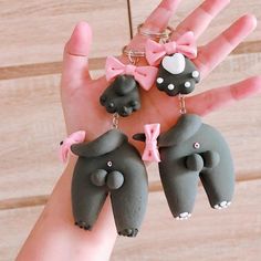 three little elephants wearing pink bows are hanging from the palm of a person's hand