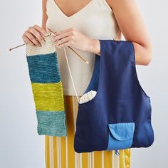 a woman is holding a bag and knitting it with her hands while wearing a white tank top