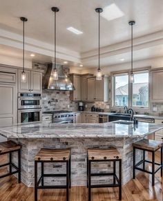 a large kitchen with an island in the middle and three stools at the end